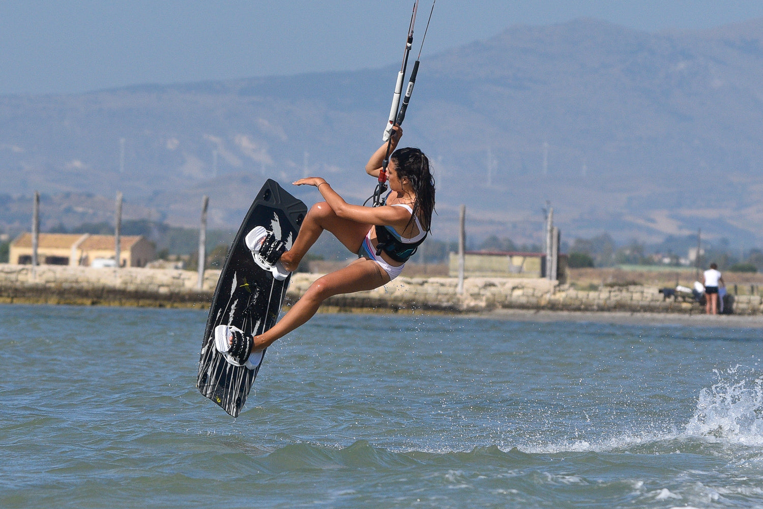 woman performing kitesurfing trick on water in Marsala Stagnone