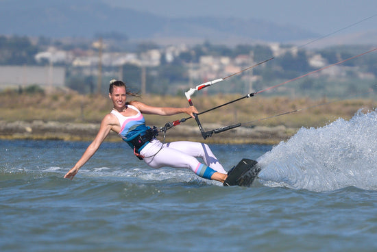 woman kitesurfing leaning into the water wearing surf gear